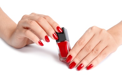 Woman with bright manicure holding bottle of nail polish on white background, closeup