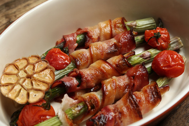 Oven baked asparagus wrapped with bacon in ceramic dish, closeup