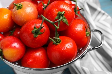 Photo of Many different ripe tomatoes in colander on table, closeup