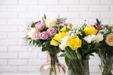 Beautiful bouquets with fresh flowers against white brick wall, closeup. Space for text