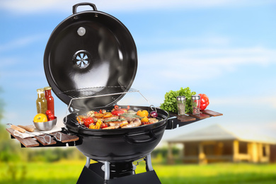 Barbecue grill with meat products and vegetables outdoors on sunny day