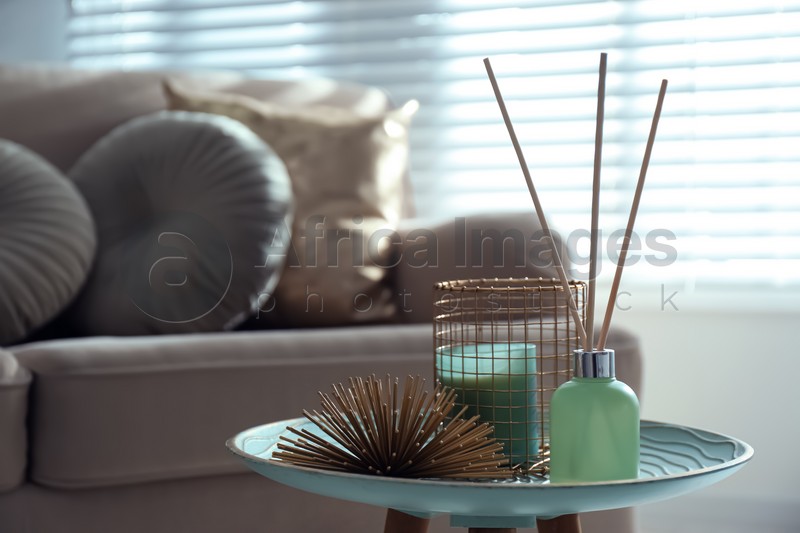 Air reed freshener, candle and decor element on table in living room. Space for text