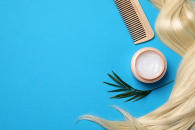 Photo of Lock of healthy blond hair, cosmetic product and comb on light blue background, flat lay. Space for text