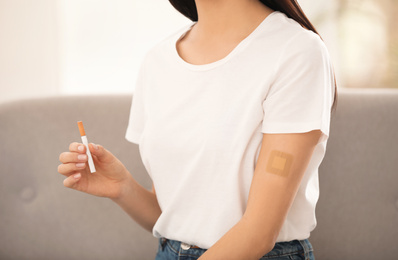 Young woman with nicotine patch and cigarette at home, closeup