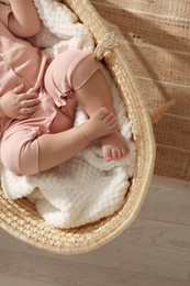 Little baby sleeping in wicker crib at home, top view