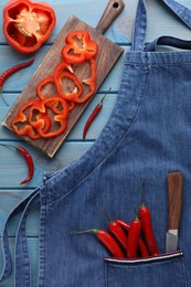 Photo of Flat lay composition with denim apron and fresh peppers on light blue wooden table
