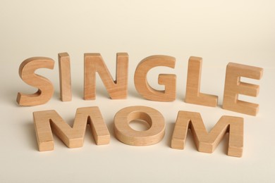 Words Single Mom made of wooden letters on beige background