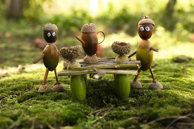 Photo of Cute figures made of natural materials on green moss outdoors