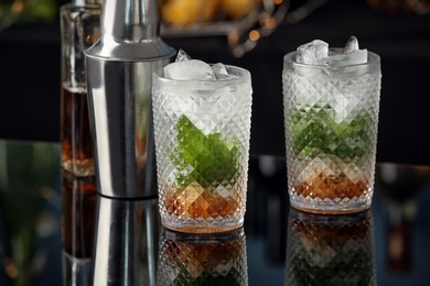 Delicious mint julep cocktail in glasses on bar counter