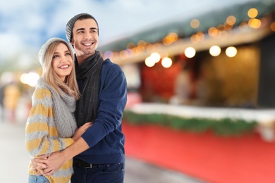 Happy couple at Christmas fair, space for text. Bokeh effect