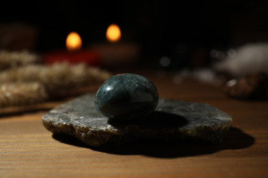Healing gemstone on wooden table against blurred background