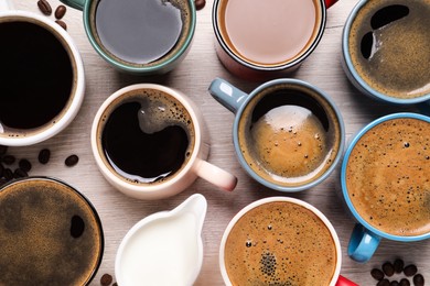 Many different cups of coffee and milk on white wooden table, flat lay