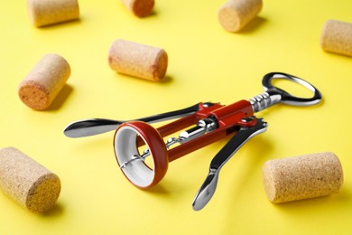 Photo of Corkscrew and wine bottle stoppers on yellow background, closeup