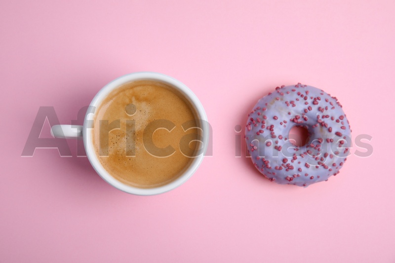 Photo of Delicious coffee and donut on light pink background, flat lay. Sweet pastries