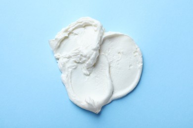 Smear of delicious cream cheese on light blue background, top view