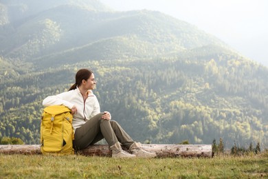 Photo of Woman with backpack resting near mountains, space for text. Tourism equipment
