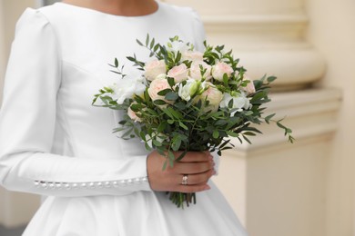 Bride wearing engagement ring and wedding dress with beautiful bouquet outdoors, closeup