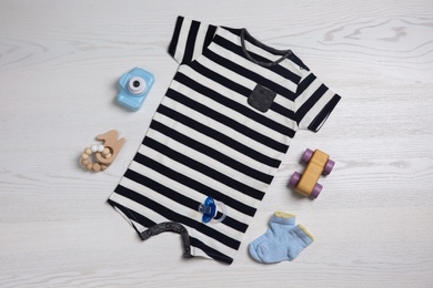 Photo of Flat lay composition with baby clothes and toys on white wooden table