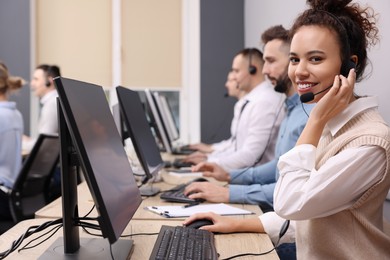 African American call center operator with headset and her colleagues working in modern office