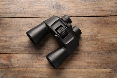 Modern binoculars on wooden table, top view