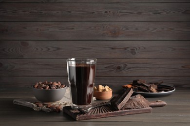 Photo of Glass of delicious hot chocolate on wooden table