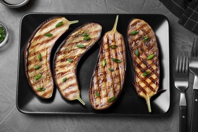 Delicious grilled eggplant halves served on grey table, flat lay
