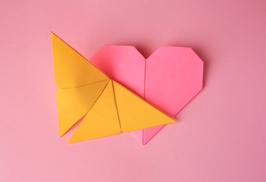 Photo of Origami art. Paper heart and butterfly on pink background, top view