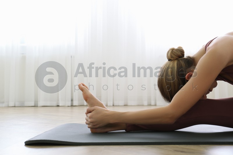 Young woman practicing head to knee asana in yoga studio. Janu Sirsasana pose