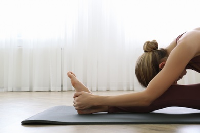 Young woman practicing head to knee asana in yoga studio. Janu Sirsasana pose