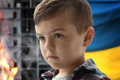 Sad little boy, national flag and fire. Stop war in Ukraine