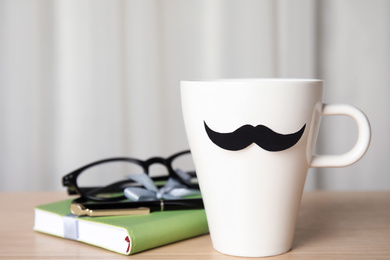 Cup with paper mustache on wooden table, closeup. Happy Father's day