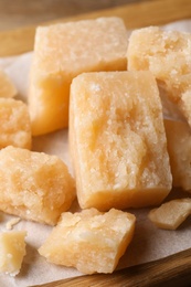 Pieces of delicious parmesan cheese on parchment, closeup view