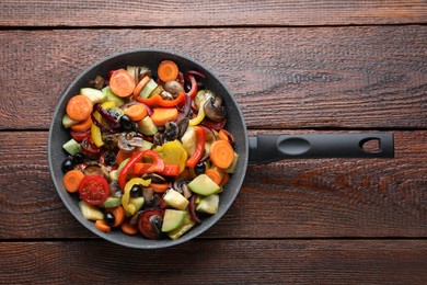 Mix of tasty vegetables in pan on wooden table, top view