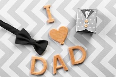 Phrase "I love dad", bow tie and gift box on color background. Father's day celebration