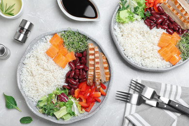 Tasty rice with beans and chicken meat served on light grey marble table, flat lay