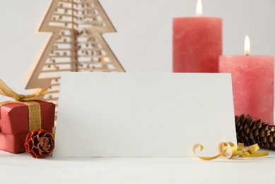 Composition with blank greeting card and Christmas decor on white wooden table, closeup. Space for text