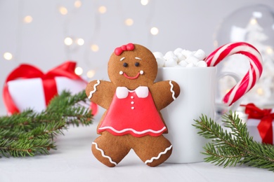 Gingerbread girl and Christmas decor on light grey table, closeup