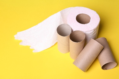 Toilet paper roll and empty tubes on color background