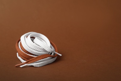 Different shoe laces on brown background. Space for text