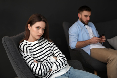 Man preferring smartphone over his girlfriend at home, focus on woman. Relationship problems