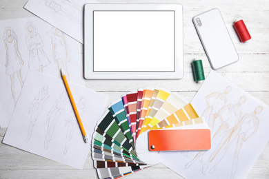 Workplace of fashion designer with color palette samples and tablet, flat lay