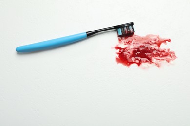 Toothbrush with blood on white table, top view and space for text. Gum inflammation