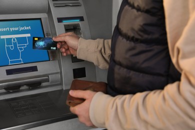 Young man with credit card near cash machine, closeup