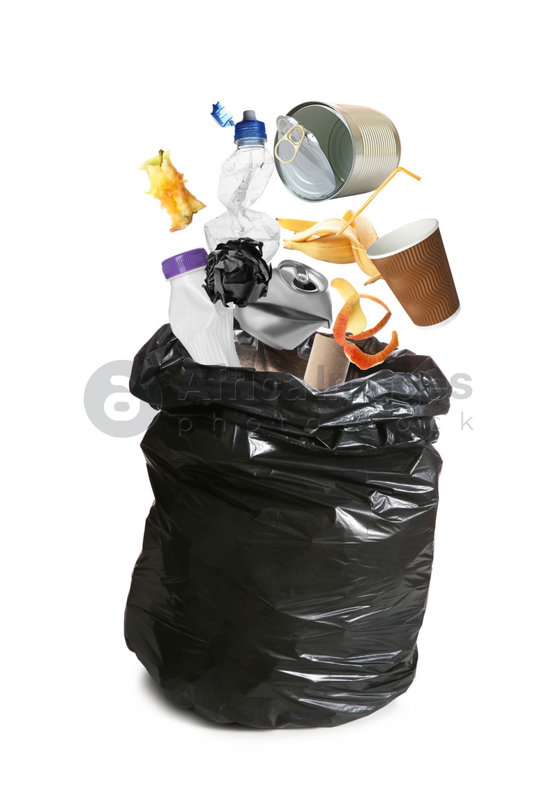 Different garbage falling into trash bag on white background