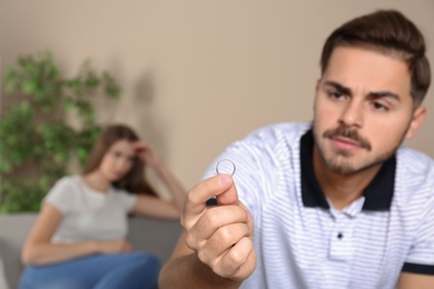 Young man looking on wedding ring after conflict with his wife at home. Relationship problems