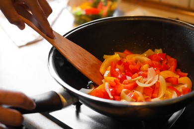 Woman cooking vegetables in frying pan indoors, closeup