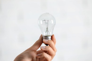 Woman holding light bulb on white background, closeup