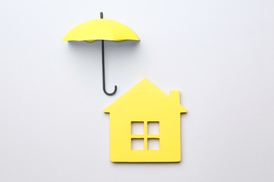 Mini umbrella and house model on white background, top view