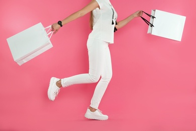 Woman running with paper shopping bags on color background. Mock up for design