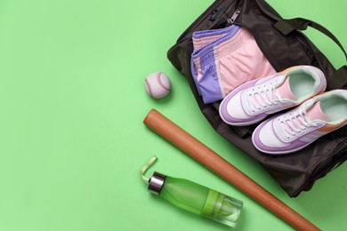 Sports bag and baseball equipment on light green background, flat lay. Space for text